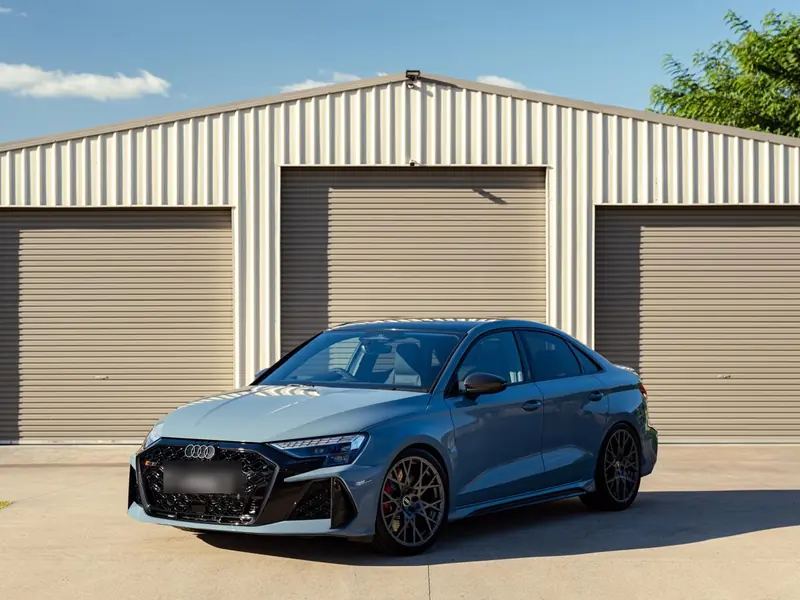 Audi RS3 sedan detailed in front of the three-bay garage