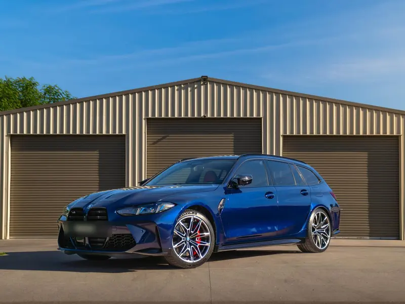 Blue BMW M3 Touring with polished paintwork on the driveway