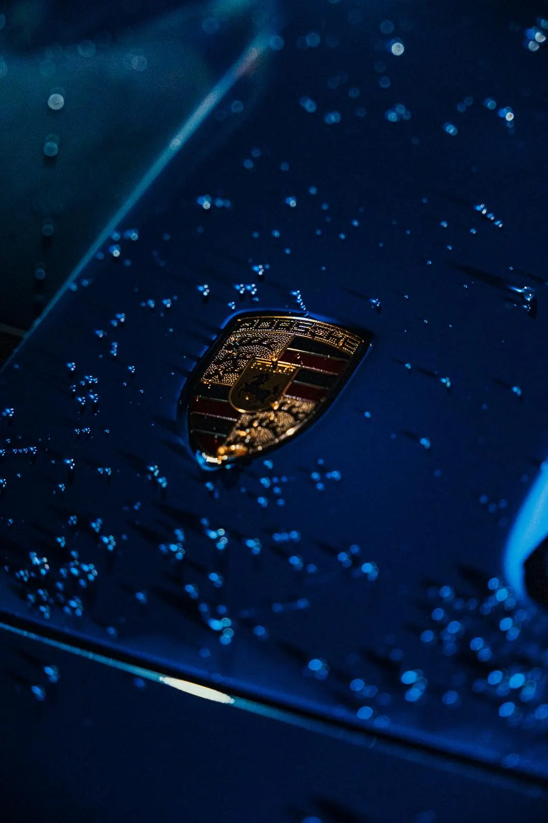 Water beading tightly over the crest on a coated blue Porsche bonnet