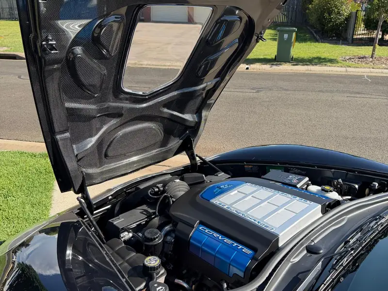 Supercharged Corvette engine bay cleaned and dressed under a raised carbon bonnet