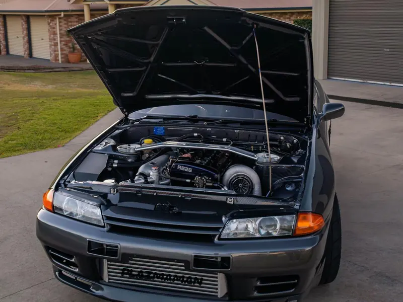 Nissan Skyline R32 with the bonnet up over a detailed RB26 engine