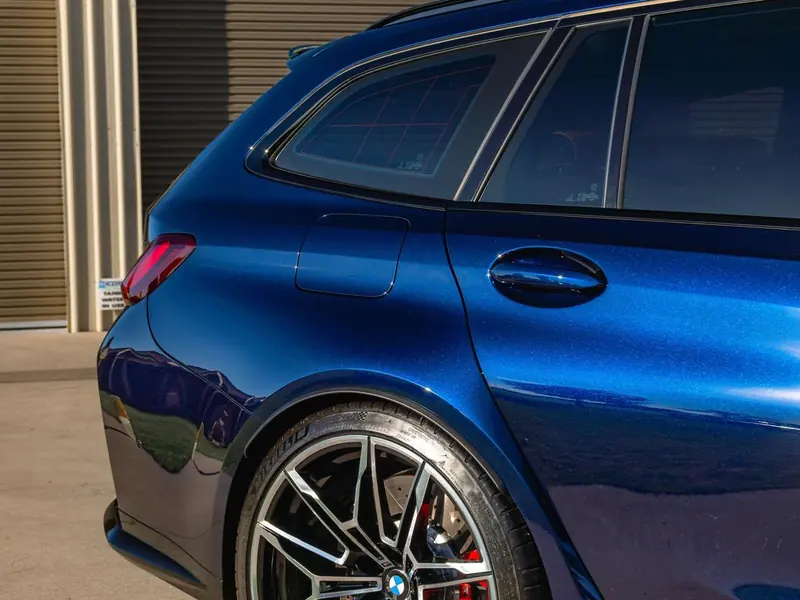 Deep gloss on the rear quarter and wheel of a blue BMW M3 Touring
