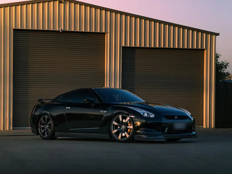 Black Nissan GT-R detailed to a mirror finish outside the garage